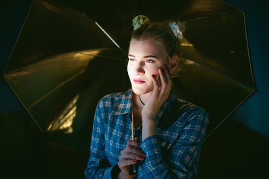studio portrait of a young woman with golden umbrella