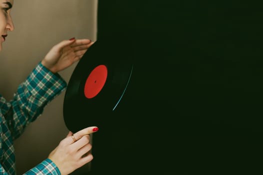 a woman with the disc. young beautiful hipster girl with old vintage vinyl record in his hands. she wants to listen to music on old player