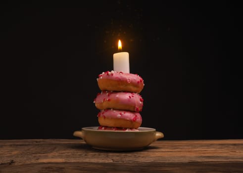 Birthday cake with stacked donuts and a burning candle