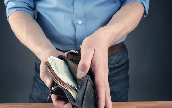 Businessman with an open wallet filled with bank notes, financial concept