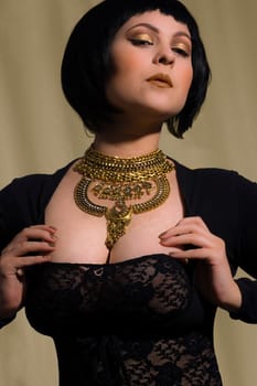 Beautiful fashion model with luxury golden necklace and black dress.