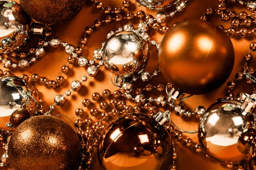Bronze shiny Christmas decoration on orange background.
