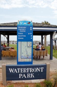 Southport, NC, USA - July 28, 2014: Waterfront Park sign below a Southport attractions map and guide. People near Southport guide map with Waterfront Park sign