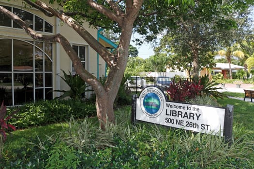 Wilton Manors, FL, USA - August 25, 2017: Building front and Welcome to the Library sign at 500 NE 26th St. Summer day Wilton Manors Library exterior and sign.