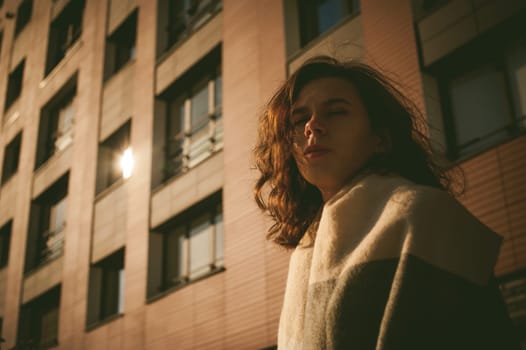 Portrait of young woman walking outdoors on warm autumn afternoon. Against the background of the house