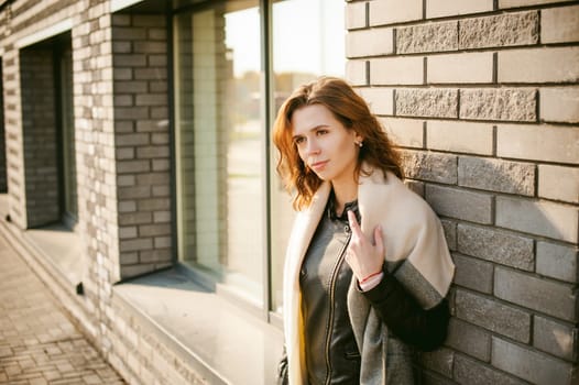 Portrait of young woman walking outdoors on warm autumn afternoon. Against a brick wall background