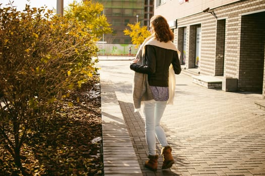 Portrait of young woman walking outdoors on warm autumn afternoon.