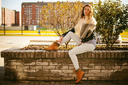 Portrait of young woman walking outdoors on warm autumn afternoon. Against the background of the house