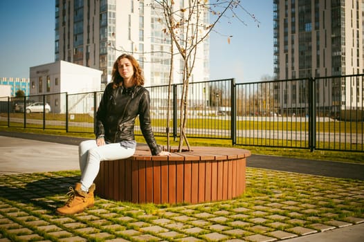 Portrait of young woman walking outdoors on warm autumn afternoon. Sitting resting