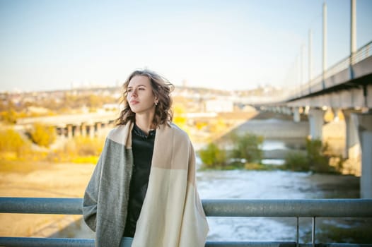 portrait of a beautiful young woman with long thin hair, a leather jacket, blue jeans. warm autumn sunny day on the stairs of the bridge.