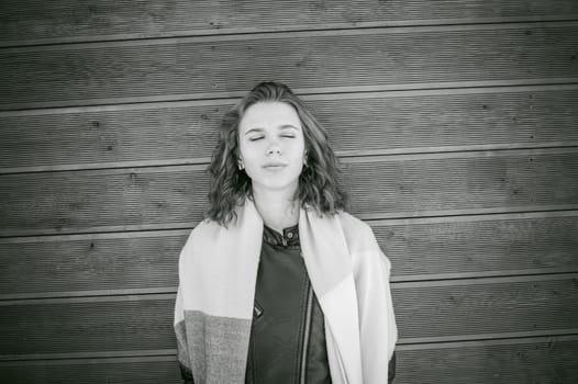 Portrait of young woman walking outdoors on warm autumn afternoon. On the background of a wooden wall