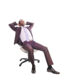 A handsome African American business man sitting on a chair relaxing, .with his hands behind his head, isolated for white background.