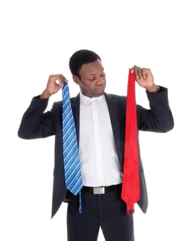 An young African American man tried to decide what tie to wear with.his dark suit, isolated for white background.