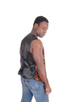 A handsome African American man in jeans and brown vest standing.in profile looking back, isolated for white background.