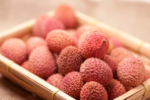 Close-up with fruits (lichi) of the lychee tree (Litchi chinensis) on coarse sack linen in the angular basket.