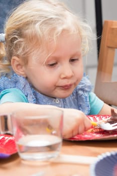 Cute little girl eating dessert from the plate
