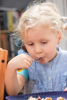 Cute little girl eating dessert from the plate with fork