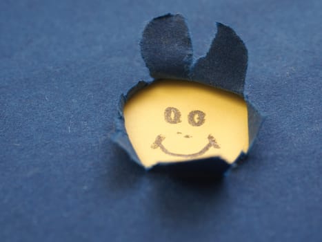 Abstract cheerful bunny face on blue paper with space for text