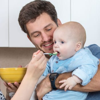 Young father holding his baby to be nourished by his mother