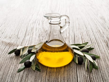 Olive oil and olive branch on wooden table
