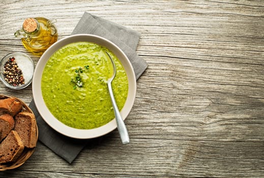 Fresh healthy green soup on wooden background overhead shoot.