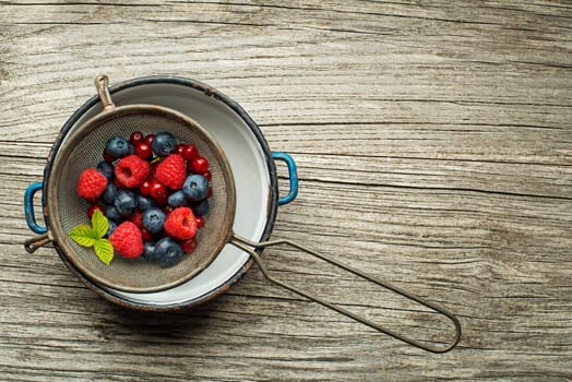 Mix of fresh berries in a bowl on wooden background