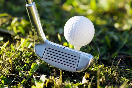 Close-up photo of golf club and golf ball on the grass.