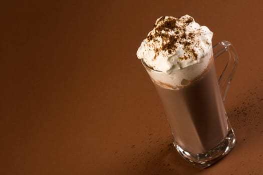 Hot chocolate drink with whipped cream on brown background.