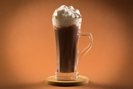 Hot chocolate drink with whipped cream on brown background.
