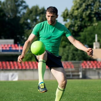 The soccer player is playing and shooting the ball in the stadium.