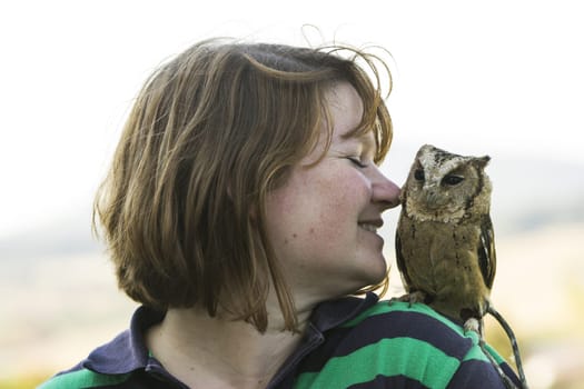 Young woman with Hindu collared owl on shoulder