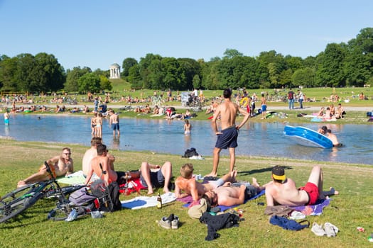 Munich, Germany, June 26, 2017: People enjoying summer, sunbathing, swimming in river Izar and relaxing on green of the Englischer Garten on 26th of June, 2017 in Munich, Germany.