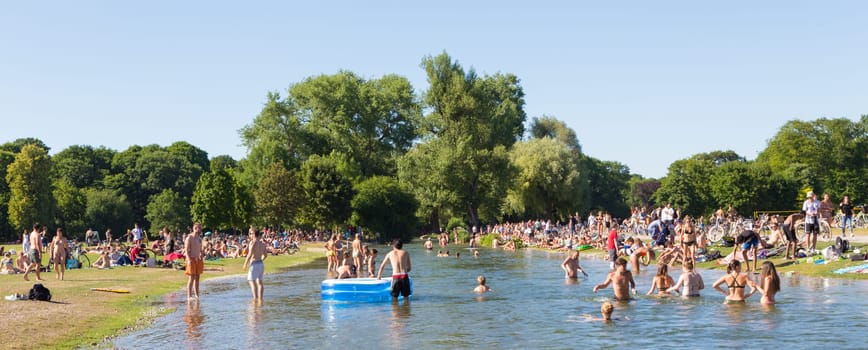 Munich, Germany, June 26, 2017: People enjoying summer, sunbathing, swimming in river Izar and relaxing on green of the Englischer Garten on 26th of June, 2017 in Munich, Germany.