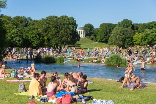 Munich, Germany, June 26, 2017: People enjoying summer, sunbathing, swimming in river Izar and relaxing on green of the Englischer Garten on 26th of June, 2017 in Munich, Germany.
