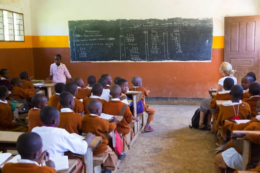 Arusha, Tanzania- Jan 26, 2015: Children in uniforms in elementary school classroom sitting behind desks listetning to teacher on January the 26th, rural area near Arusha, Tanzania, Africa.