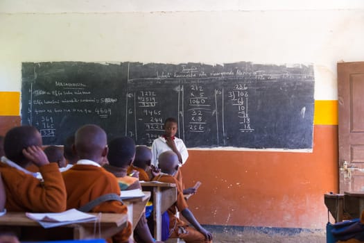 Arusha, Tanzania- Jan 26, 2015: Children in uniforms in elementary school classroom sitting behind desks listetning to teacher on January the 26th, rural area near Arusha, Tanzania, Africa.