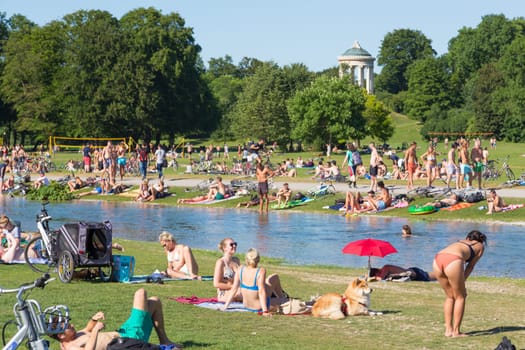 Munich, Germany, June 26, 2017: People enjoying summer, sunbathing, swimming in river Izar and relaxing on green of the Englischer Garten on 26th of June, 2017 in Munich, Germany.