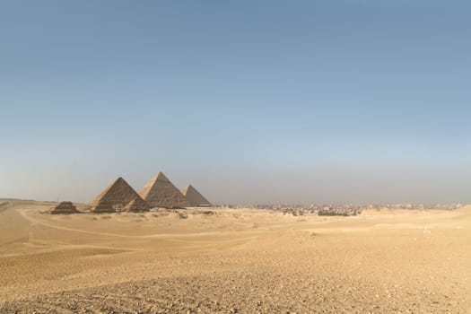 Giza pyramids in Cairo, Egypt. General view of pyramids from the Giza Plateau Three pyramids known as Queens' Pyramids on front side. Next in order from left, the Pyramid of Menkaure, Khafre and Chufu