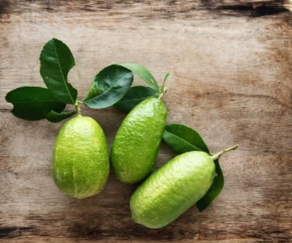Top view pesticide free fresh organic lemons with leaves on wooden table background, imperfect insect bites.