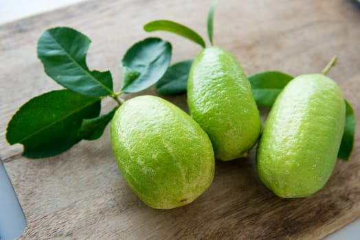 Pesticide free fresh organic lemons with leaves on wooden table background, imperfect insect bites.