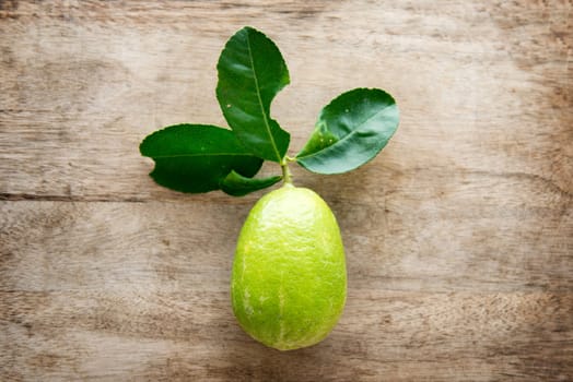 Top view fresh organic lemon with leaves on wooden table background, pesticide free, imperfect insect bites.