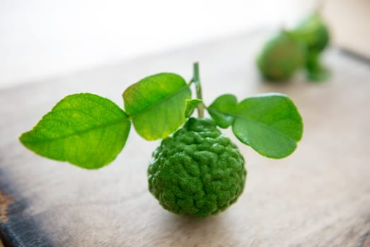 Pesticide free fresh organic kaffir lime with leaves on wooden background.