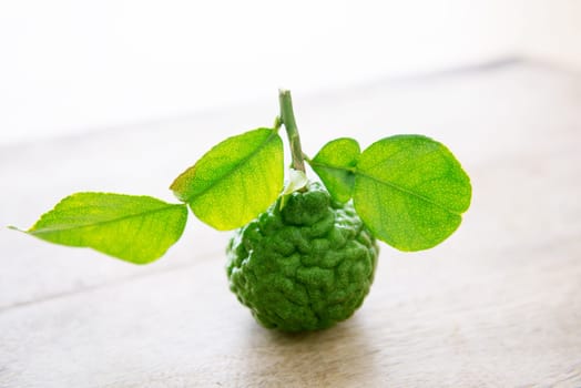 Fresh organic kaffir lime with leaves on wooden background.