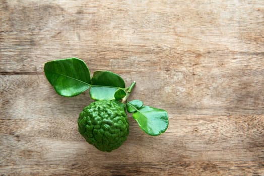 Pesticide free fresh organic kaffir lime with leaves on wooden background, top view.