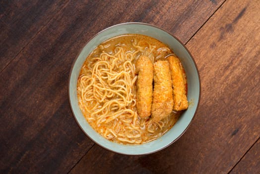 Top view Spicy curry noodles. Asian cuisine, ready to serve on wooden dining table.
