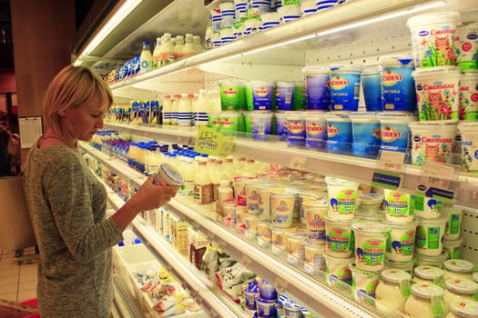woman shopping at a supermarket in the dairy department. Yogurts and others dairy produce on the shelves of shop