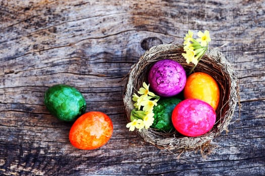Happy Easter! An Easter nest with colorful Easter eggs and key flowers