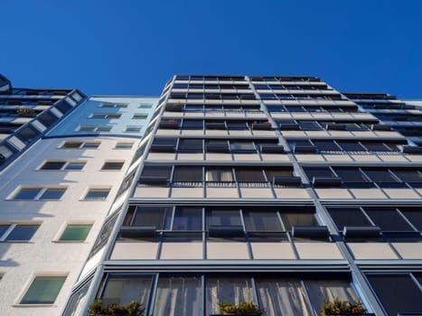 Underside view of a house façade with glazed balconies under blue sky in Berlin-Adlershof.