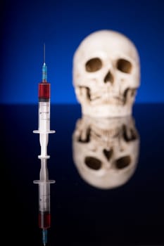 Blurry Skull and syringe, isolated on black blue background with glossy reflection