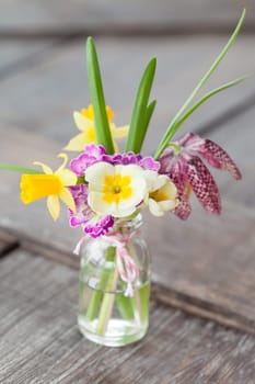 Colourful bouquet of spring flowers in a small bottle